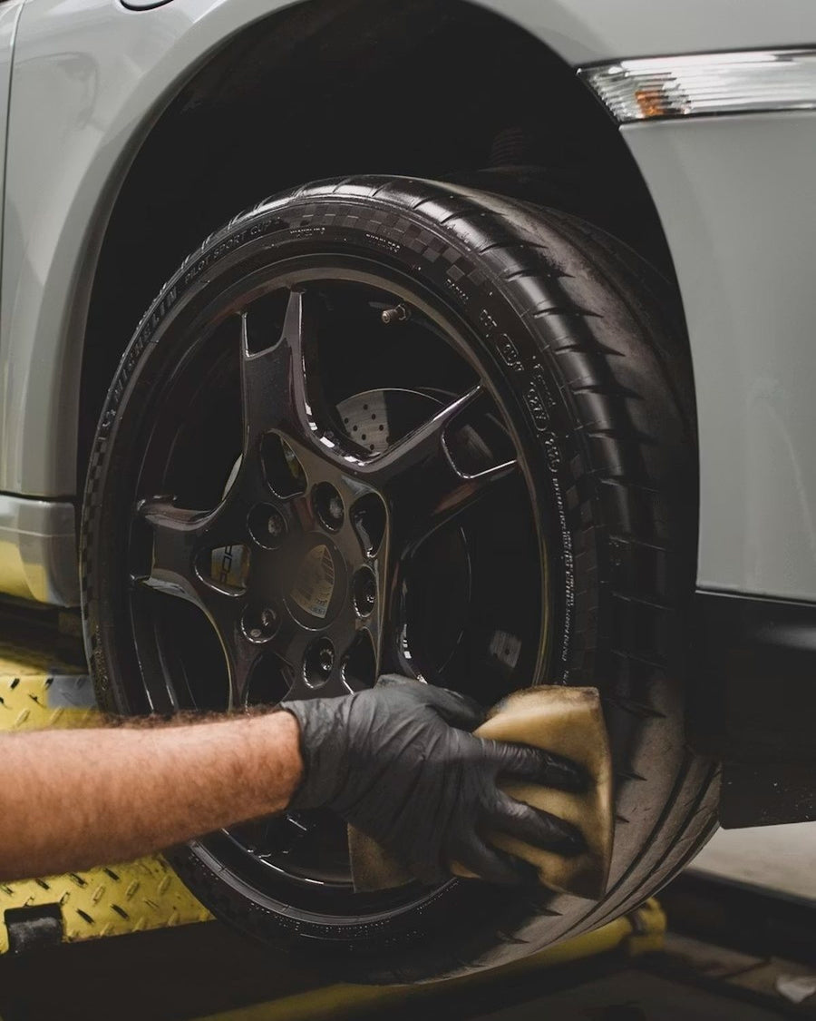 Detailer hand-cleaning an alloy wheel